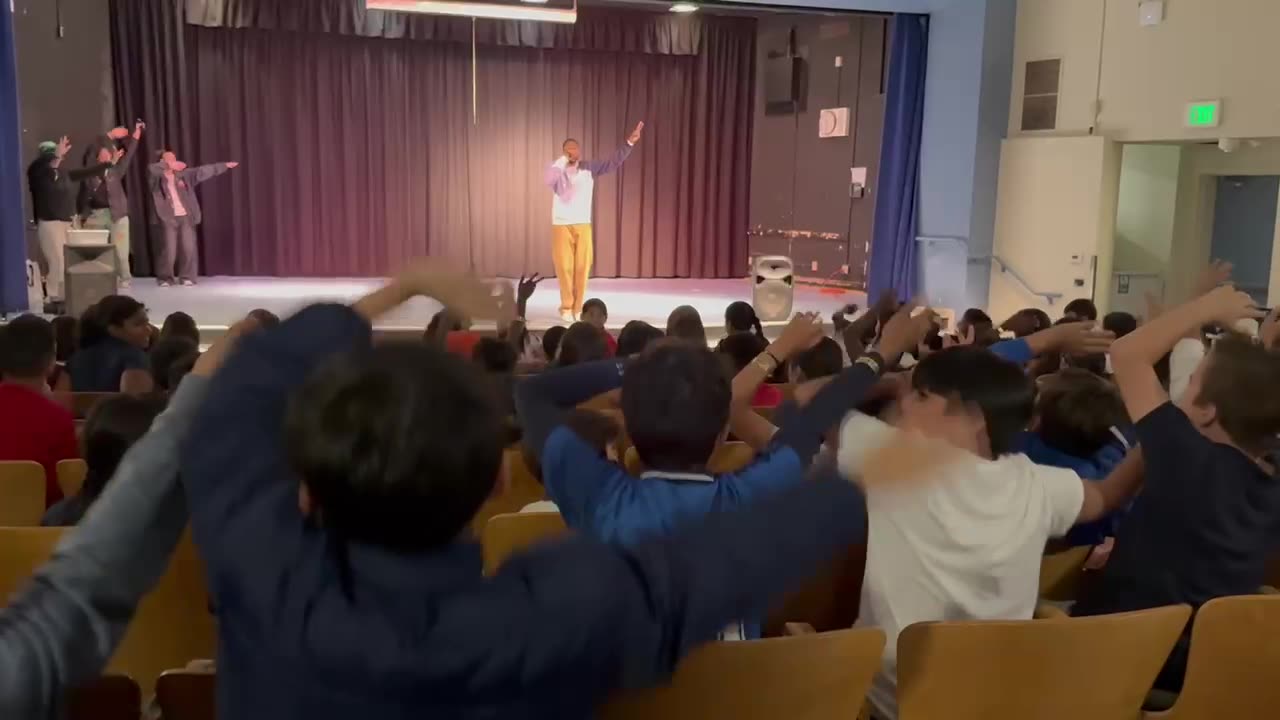 Students with arms raised during a Music is Medicine assembly