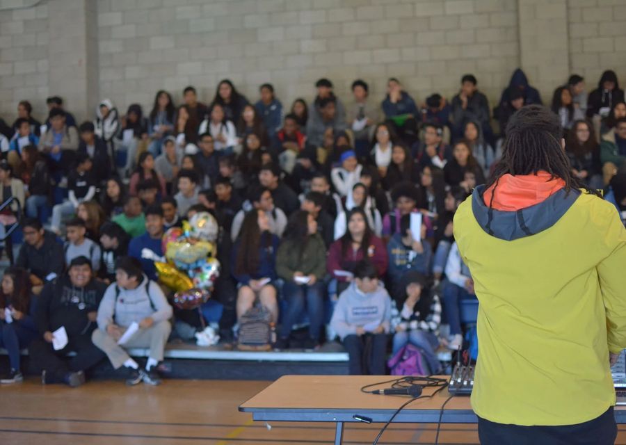 Students at an AIM 4 The Heart assembly, arms raised