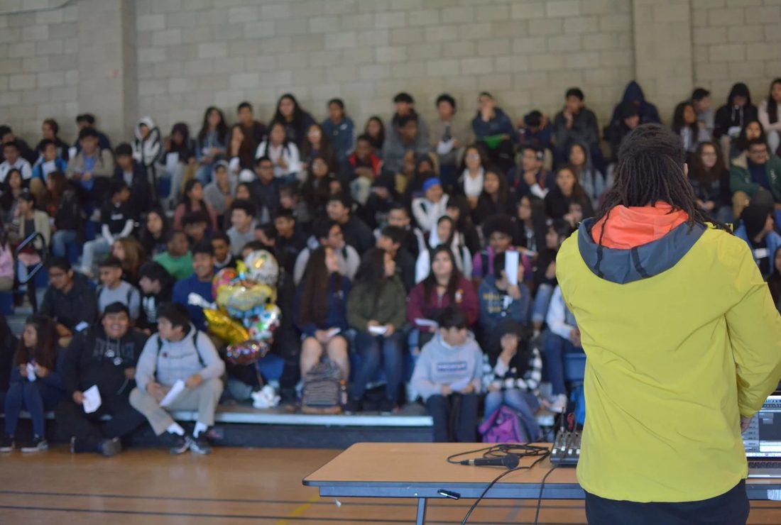 Young people with arms raised at an AIM 4 The Heart assembly