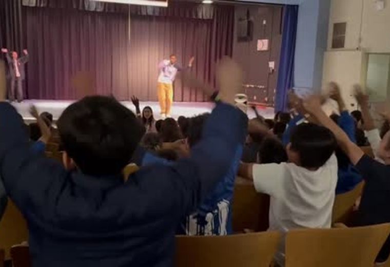 A performer on stage at a school assembly